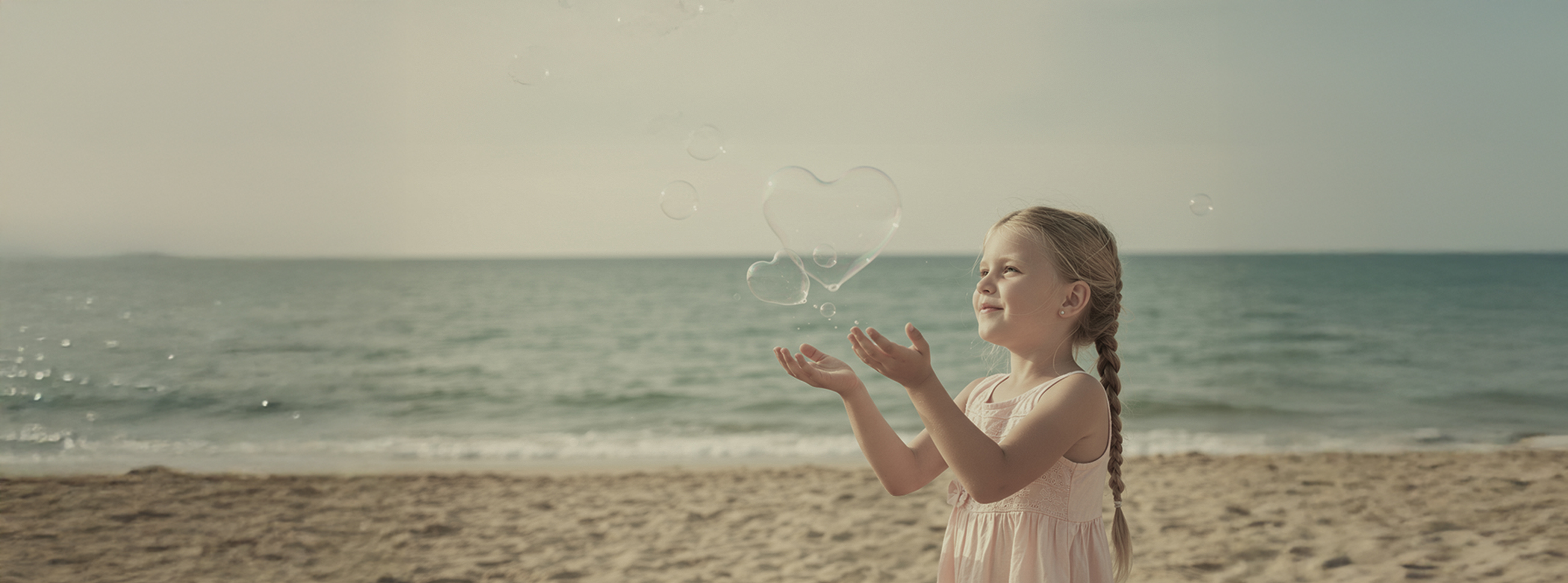 海辺で遊ぶ少女とシャボン玉の写真